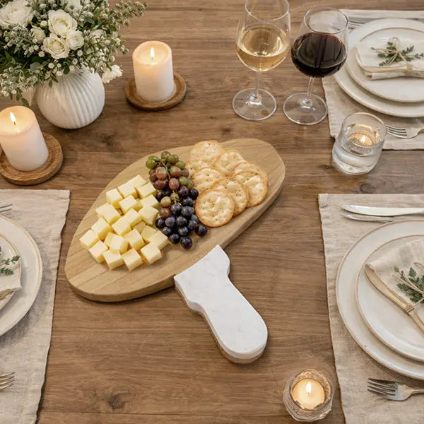 Marble and Wood Mushroom Cutting Board on a rustic table with cheese, grapes, and crackers.