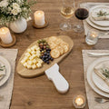 Marble and Wood Mushroom Cutting Board on a rustic table with cheese, grapes, and crackers.