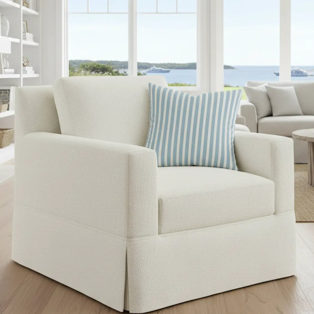 Hampton Stripe Throw Pillow on a white armchair with blue coastal stripes in a bright seaside living room.