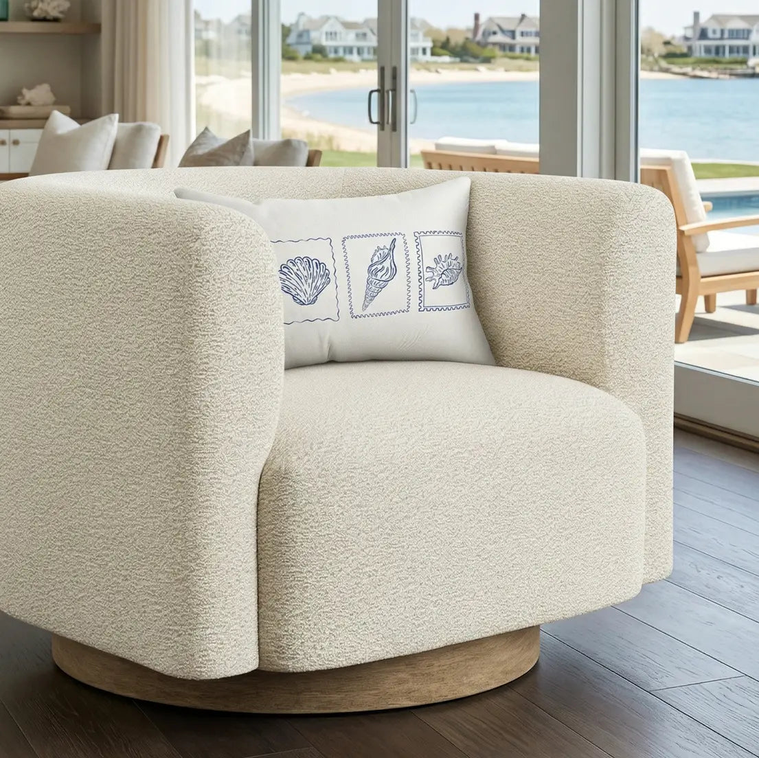 Seashell Reverie Lumbar Pillow on a cream textured armchair; white with blue seashell illustrations.