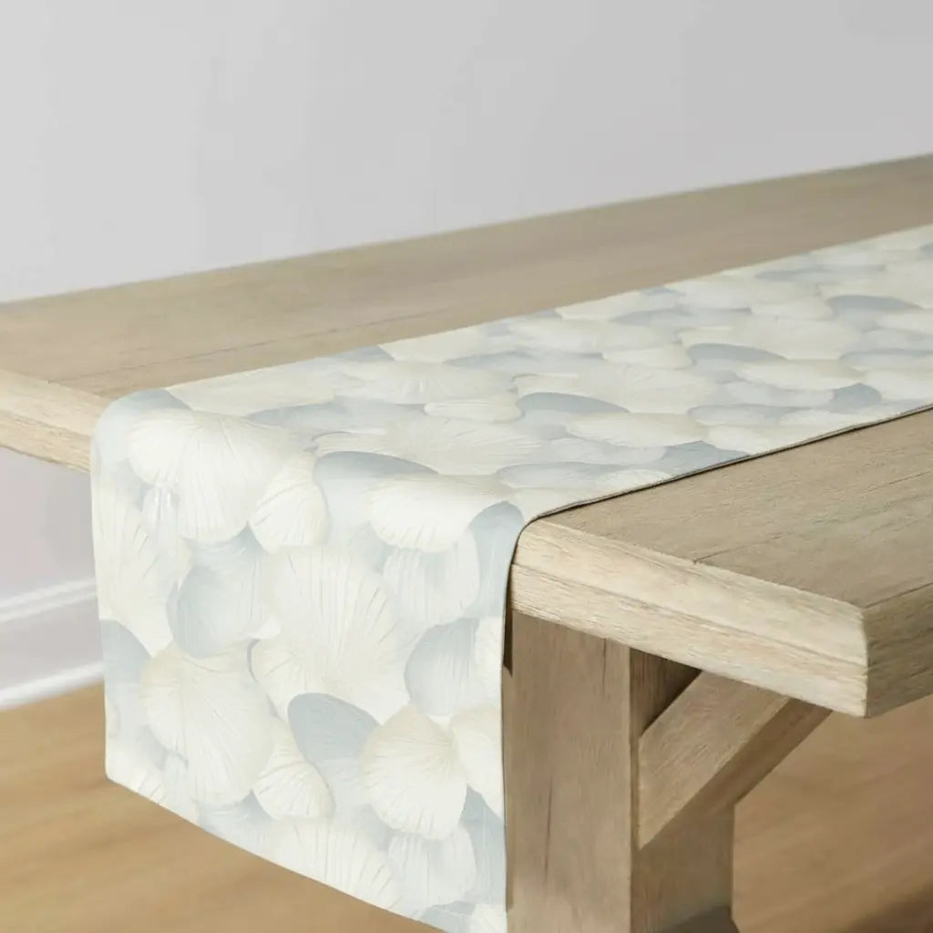 Seashell Coastal Table Runner with pale blue and cream shell pattern draped over a wooden table.