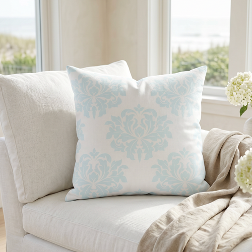 Aqua damask pattern decorative pillow styled on a cream couch in a beach house living room.