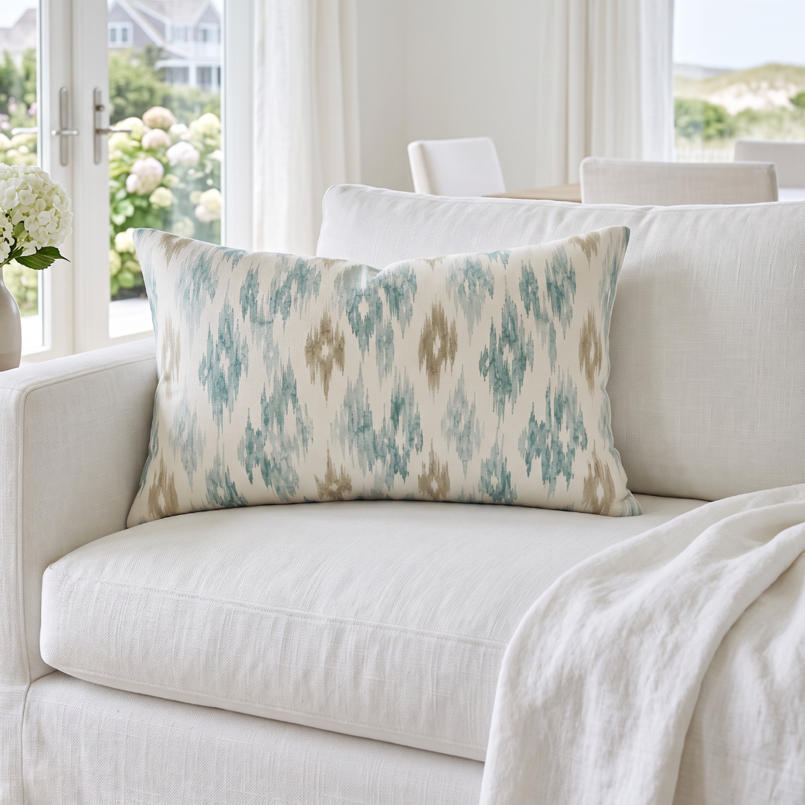 Aqua and tan ikat lumbar throw pillow styled on a neutral linen sofa for modern coastal living room decor