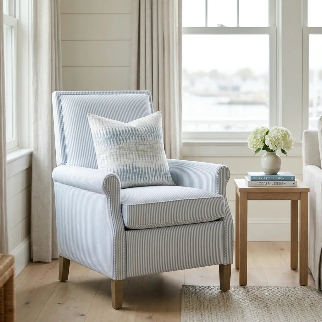 Stonewash Ikat Throw Pillow on a light blue striped armchair in a coastal living space.