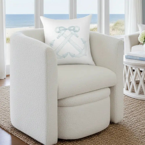 Anchorline Pillow with a pale blue anchor motif on white fabric, placed on a coastal armchair by a seaside window.