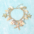 Coastal shell starfish pearl charm station bracelet styled as beach inspired jewelry on a wrist.
