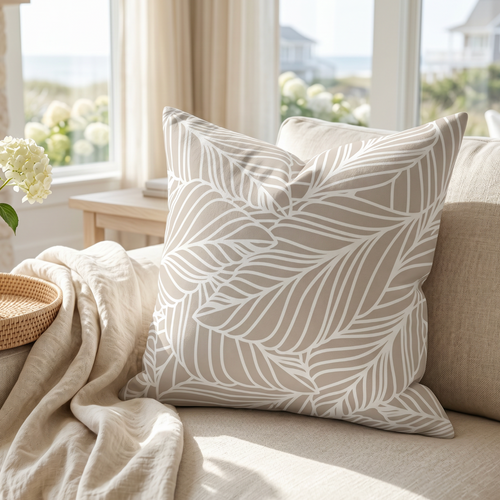 Beige leaf pattern throw pillow styled on a neutral coastal sofa.