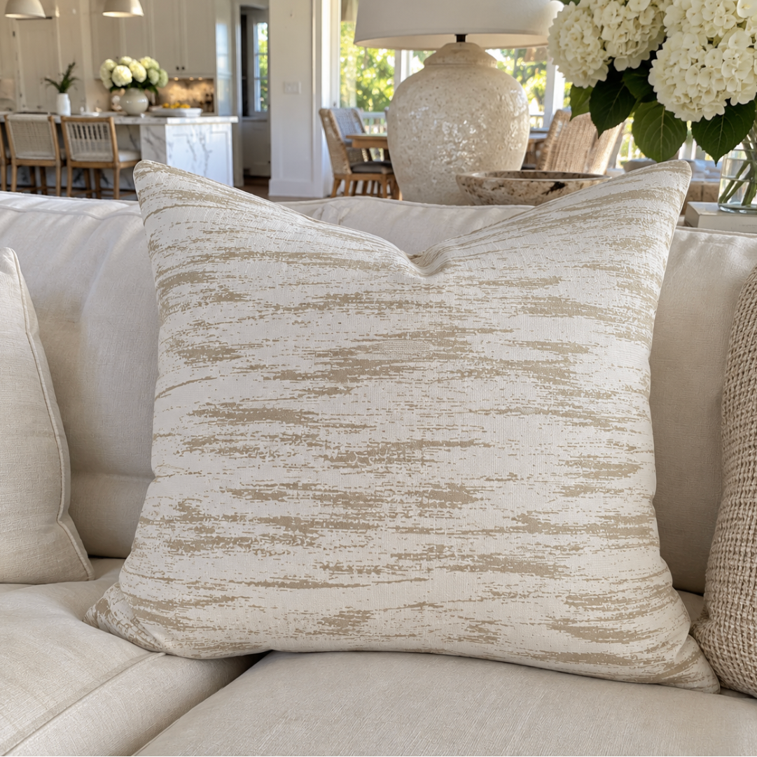 Beige and taupe striped throw pillow styled in an elegant coastal living room.