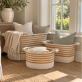 Coastal-style woven rope storage baskets arranged beside a neutral sofa with solid-colored pillows and cozy throws.