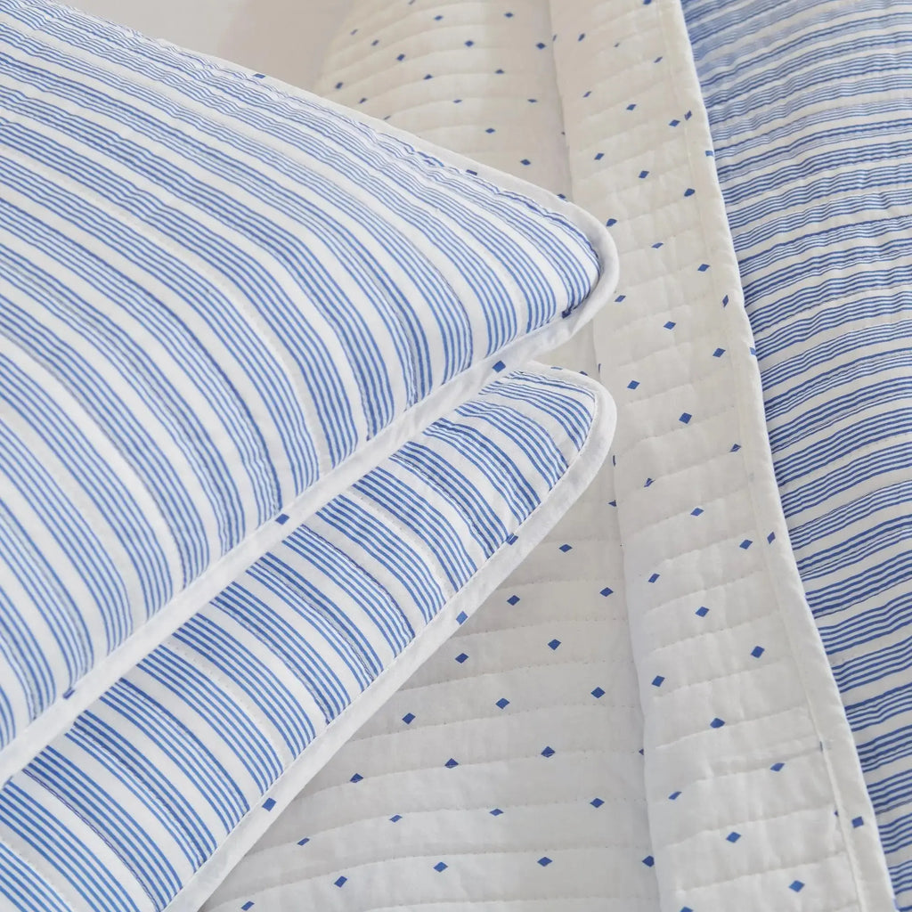Blue striped quilt and shams creating nautical bedding in a beach house bedroom