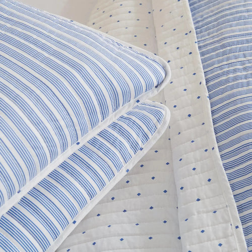 Blue striped quilt and shams creating nautical bedding in a beach house bedroom