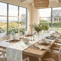 Blue and green coastal botanical table runner layered with rattan placemats and glassware.