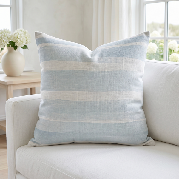 Coastal blue and white throw pillow styled on a light sofa in a beach inspired living room