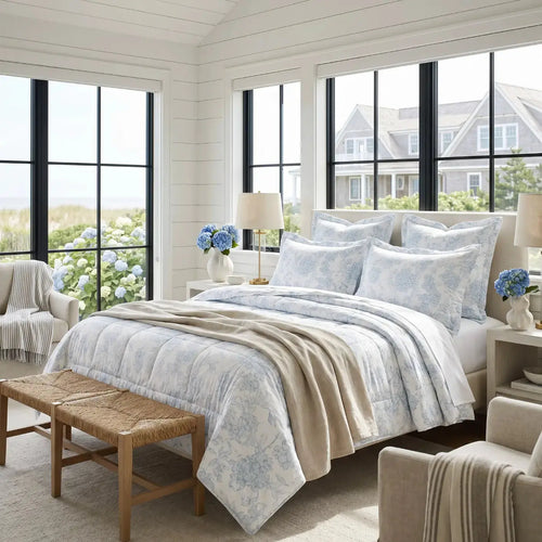 Blue and white floral comforter on a bed in a coastal bedroom with white sheets