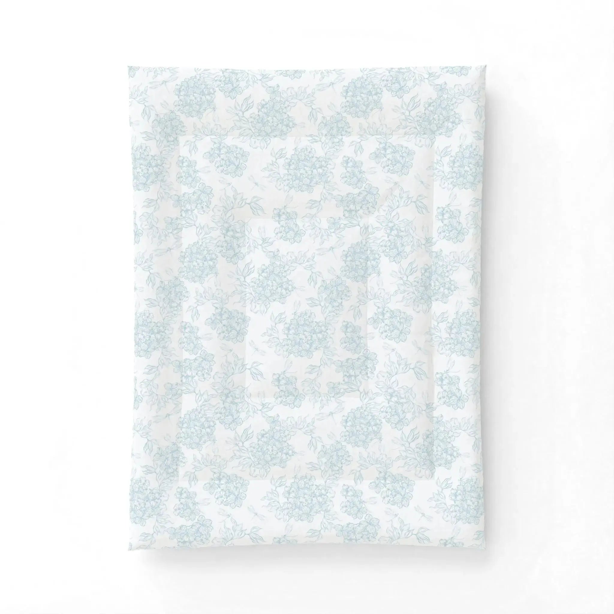 Blue and white floral comforter styled in a beach house bedroom with neutral decor accents.