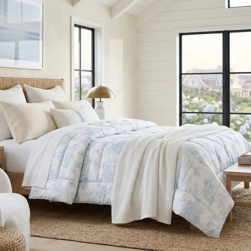 Blue and white floral comforter styled in a beach house bedroom with neutral decor.