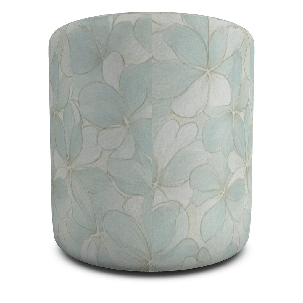 Two soft blue cylinder ottomans featuring oversized hydrangea-style flowers on a neutral area rug.