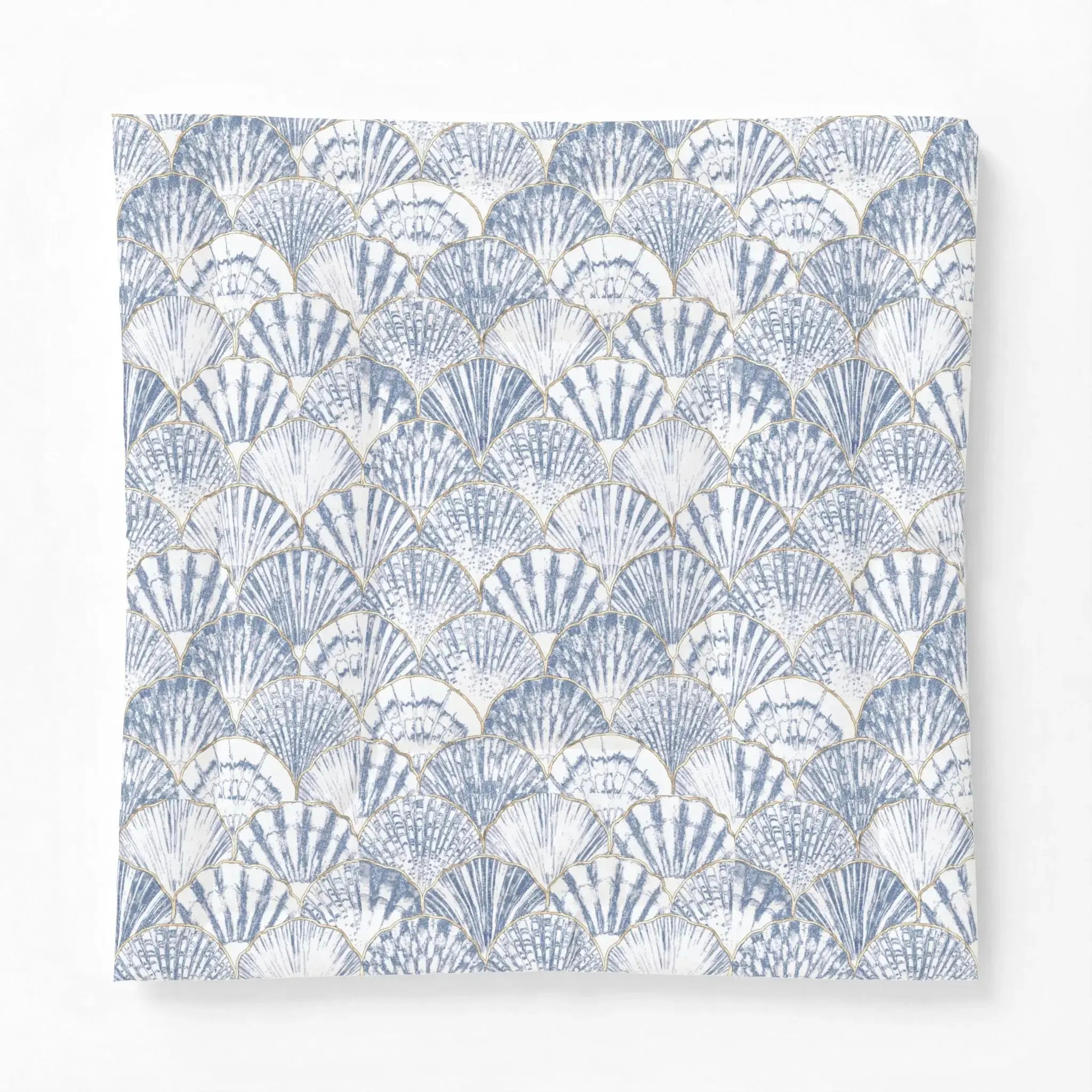 Blue and white seashell comforter adding a nautical pattern to a bright seaside bedroom