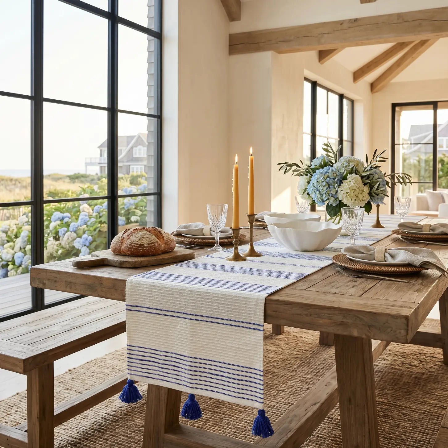 Blue and white stripe woven table runner on a farmhouse table in a bright coastal kitchen.
