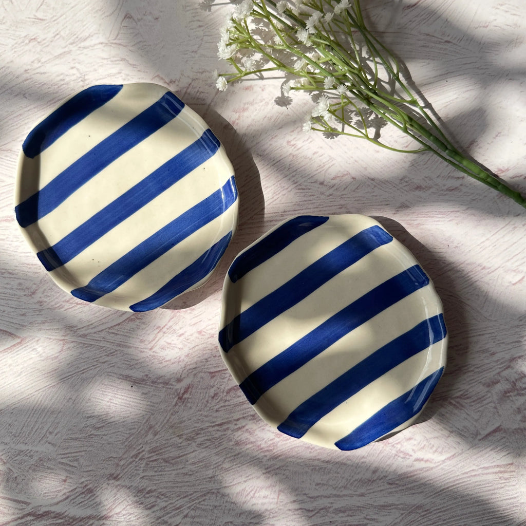 Closeup of blue and white striped hand-painted plate showing brushstroke detail.