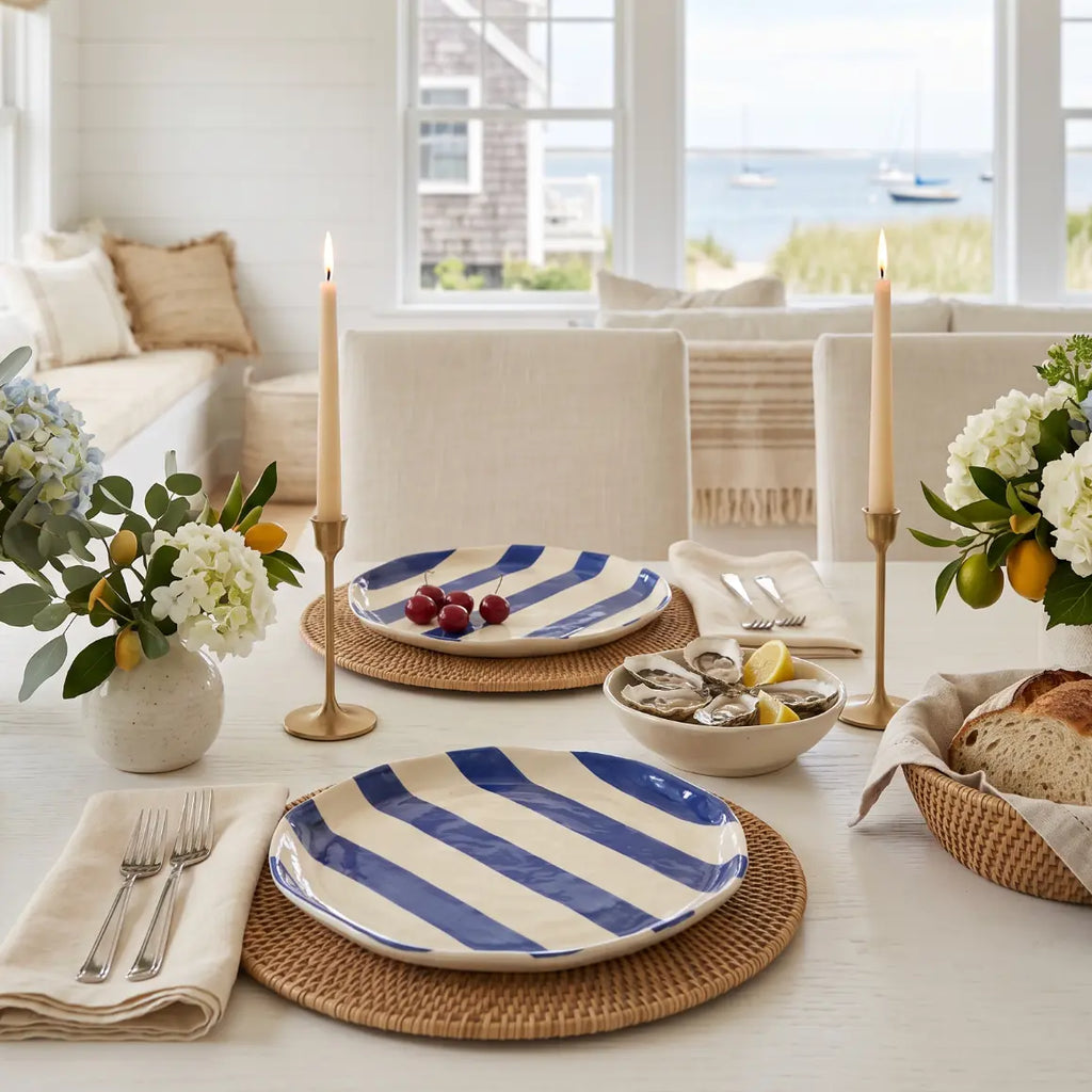 Set of four blue and white striped hand-painted plates on a coastal dining table