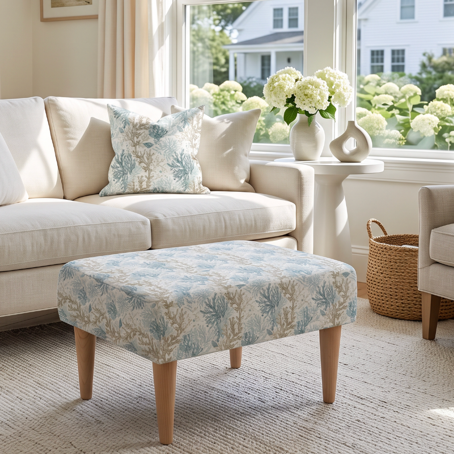Cream bench ottoman with muted aqua and taupe coral motifs, paired with a white slipcovered sofa and neutral rug.