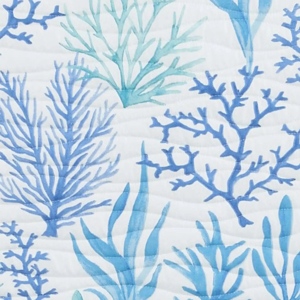 Blue coral quilt on a bed in a relaxed beach house bedroom with simple decor.