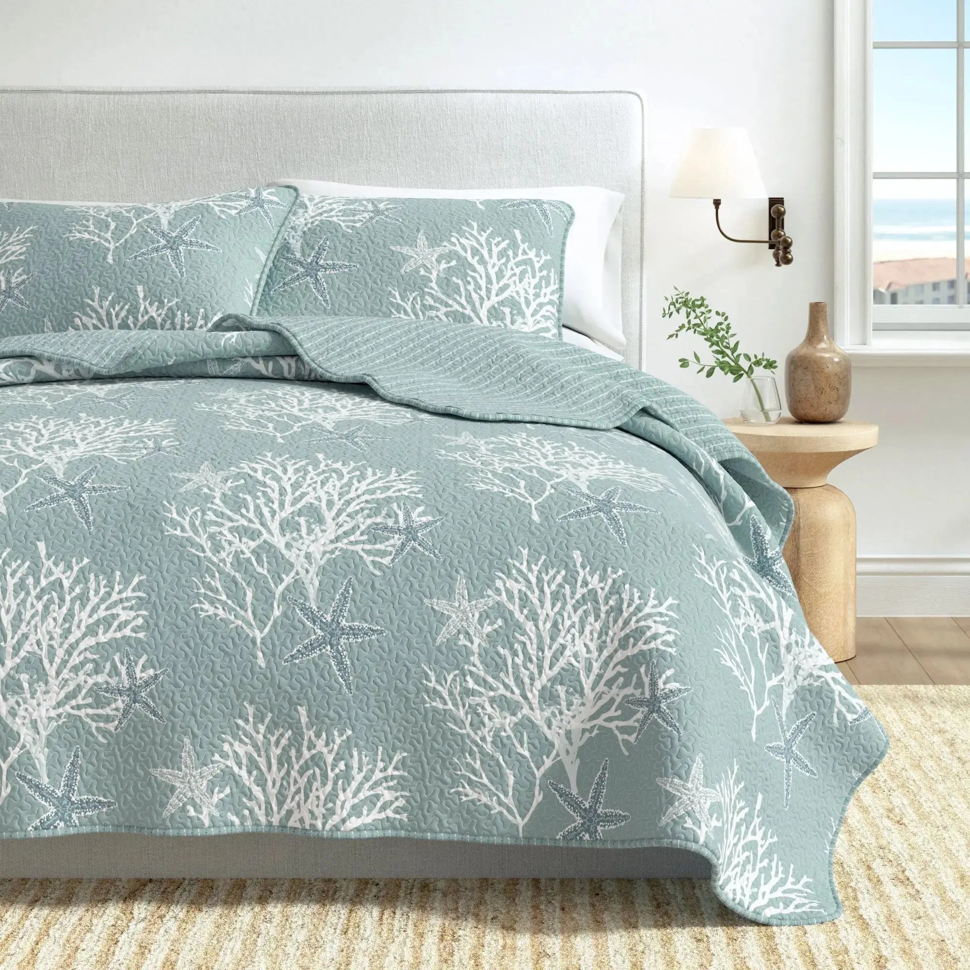 Blue coral pattern quilt set layered with white pillows for relaxed beach house style