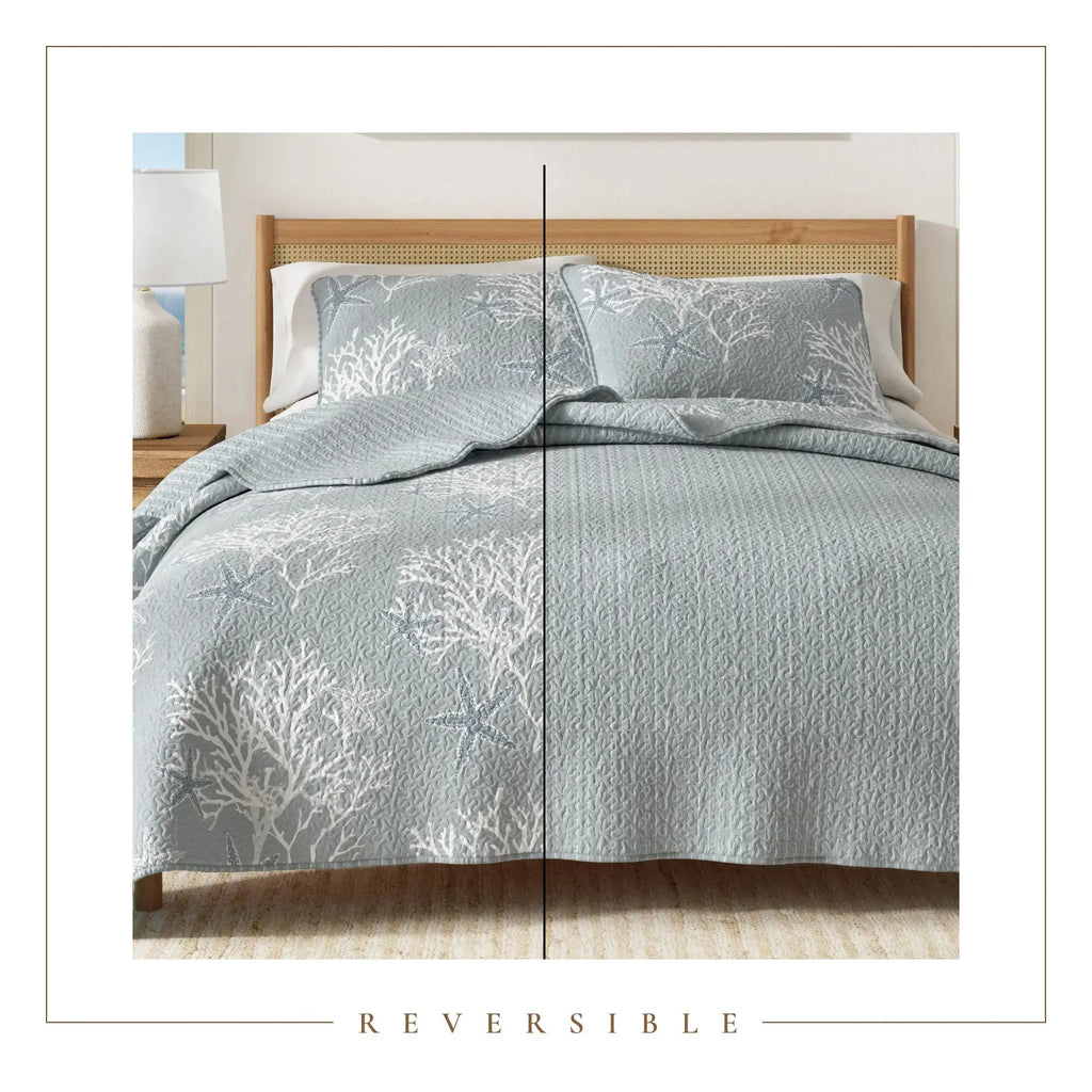 Blue coral pattern quilt set on a bed with white pillows in a bright coastal bedroom