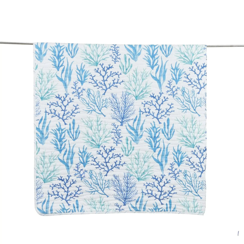 Blue coral motif quilt on a queen bed in a light, airy seaside bedroom