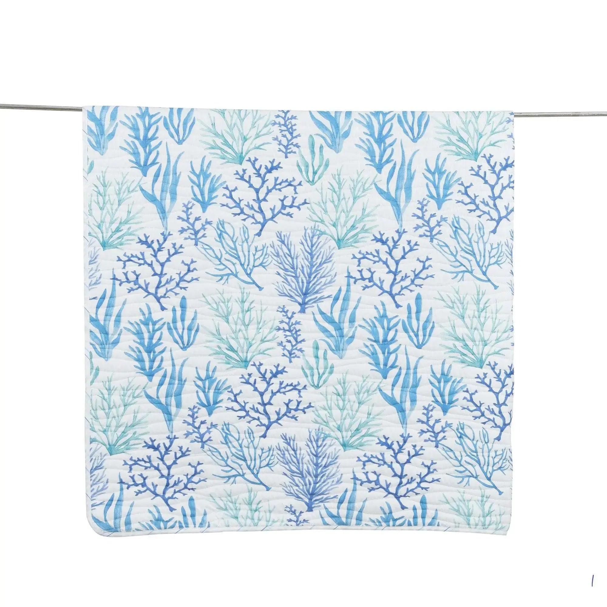 Blue coral motif quilt on a queen bed in a light, airy seaside bedroom