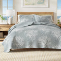 Blue coral pattern quilt set on a king bed with white pillows and natural decor accents