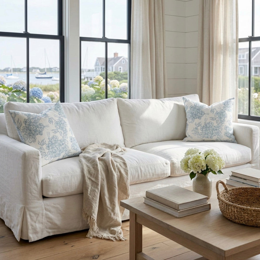 Blue and white flower pattern decorative pillow styled on a cream couch in a beach house living room
