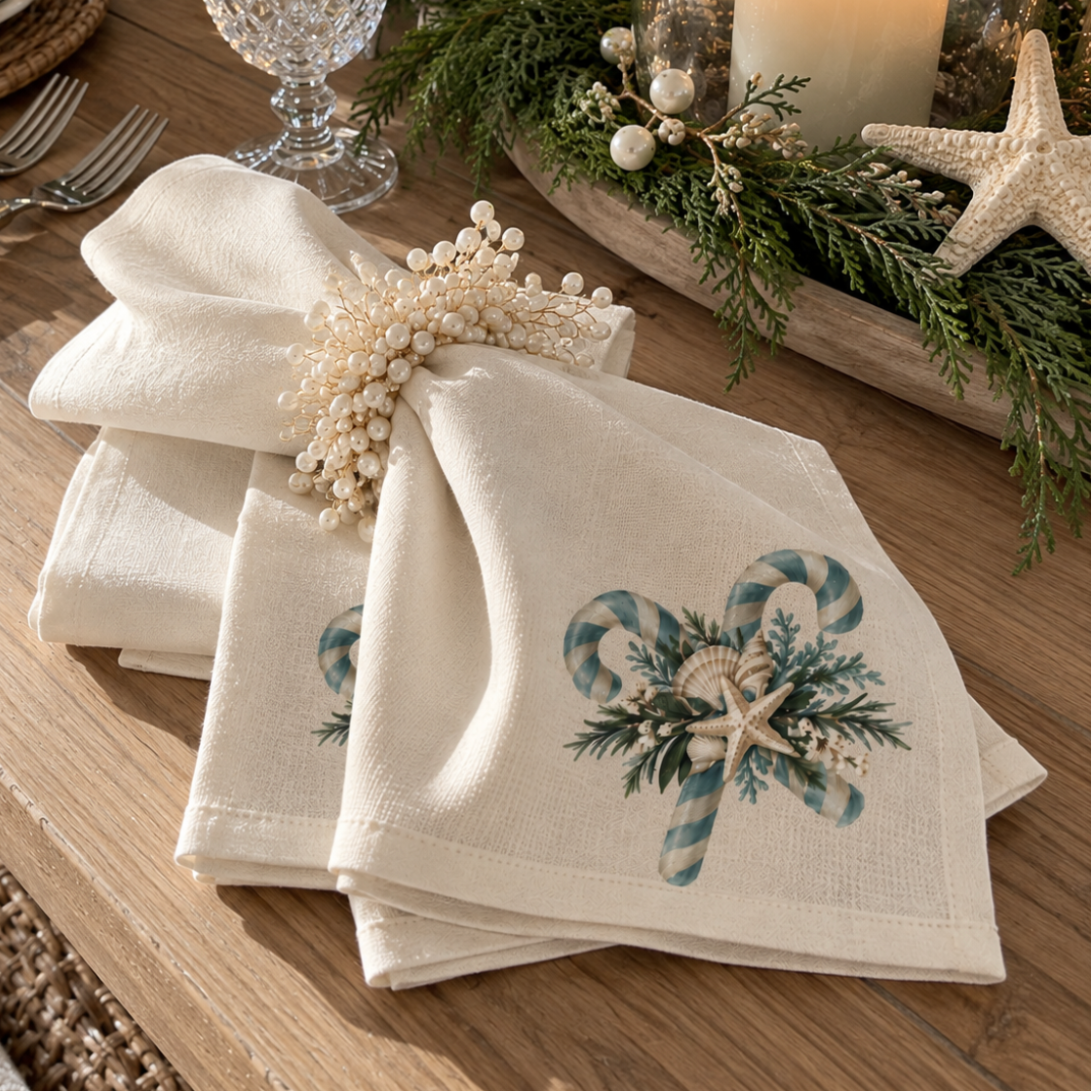 Blue-green candy cane Christmas napkin design with seashells, starfish, and festive greenery on textured ivory fabric.