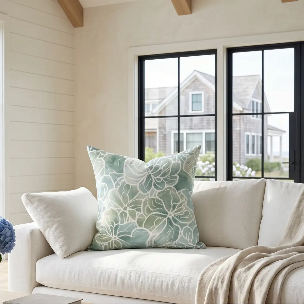 Blue green coastal flora throw pillow on a neutral sofa in a coastal living room