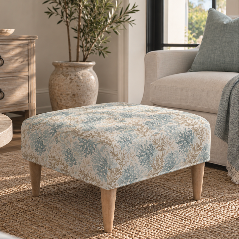 Patterned coastal ottoman footstool with seaweed motif fabric on a jute rug, styled in a beach house living room