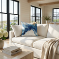 Abstract blue and white marble print decorative pillow styled on a cream couch in a modern living room.