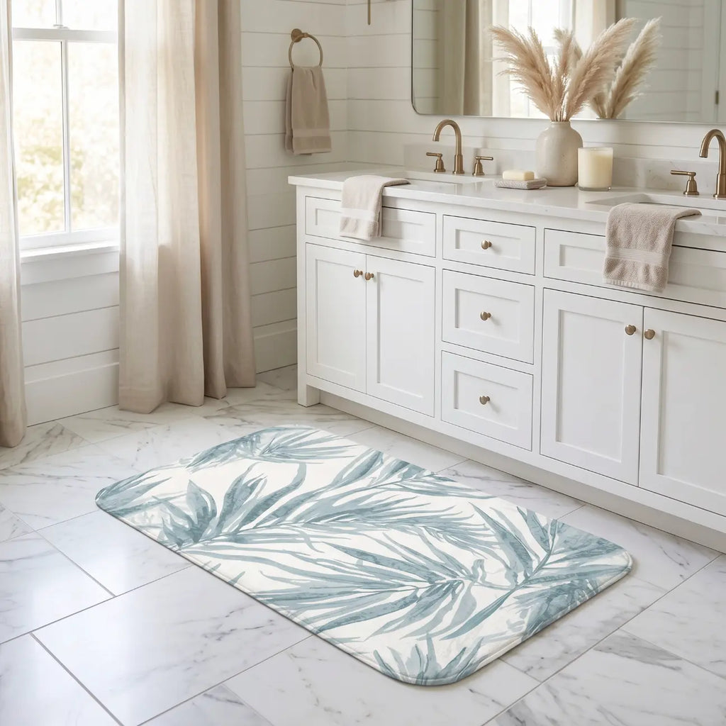 Blue palm leaf bath mat placed in front of a shower in a beach house.