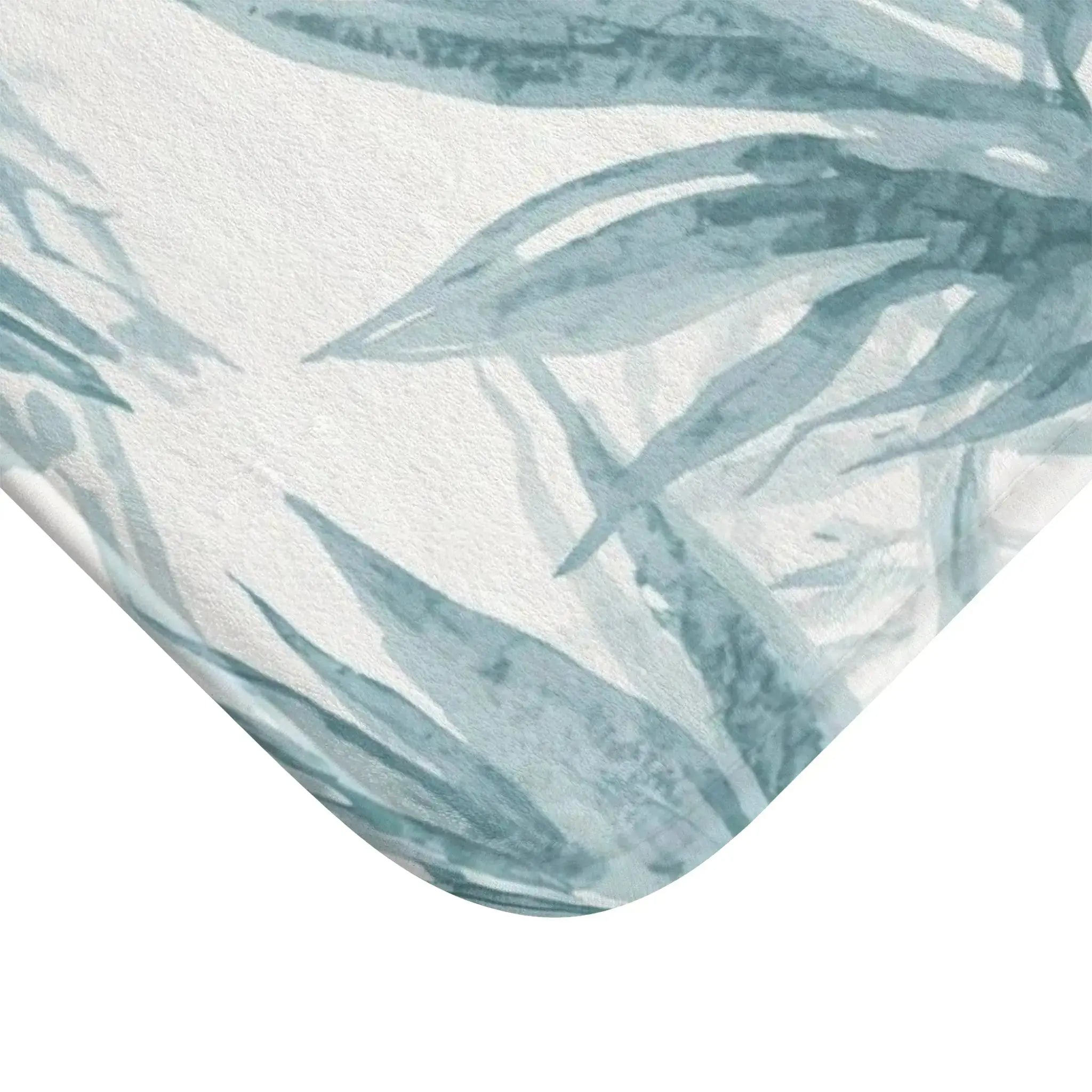 Closeup of blue palm leaf pattern on soft coastal bath mat.