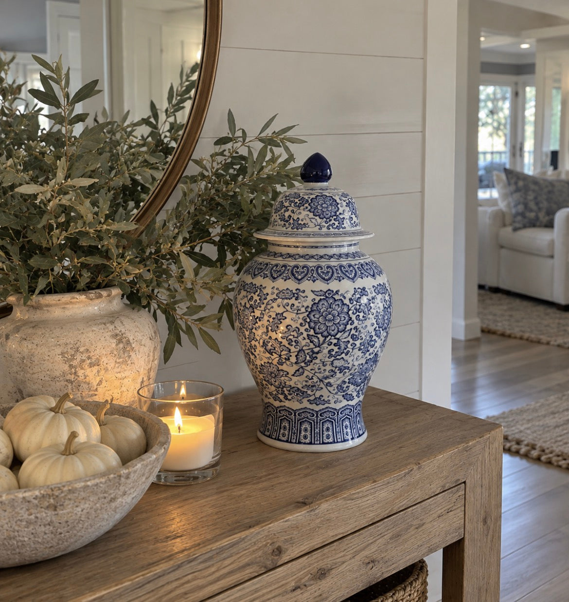Blue and white chinoiserie jar styled on a coastal console table with hydrangeas and woven accents