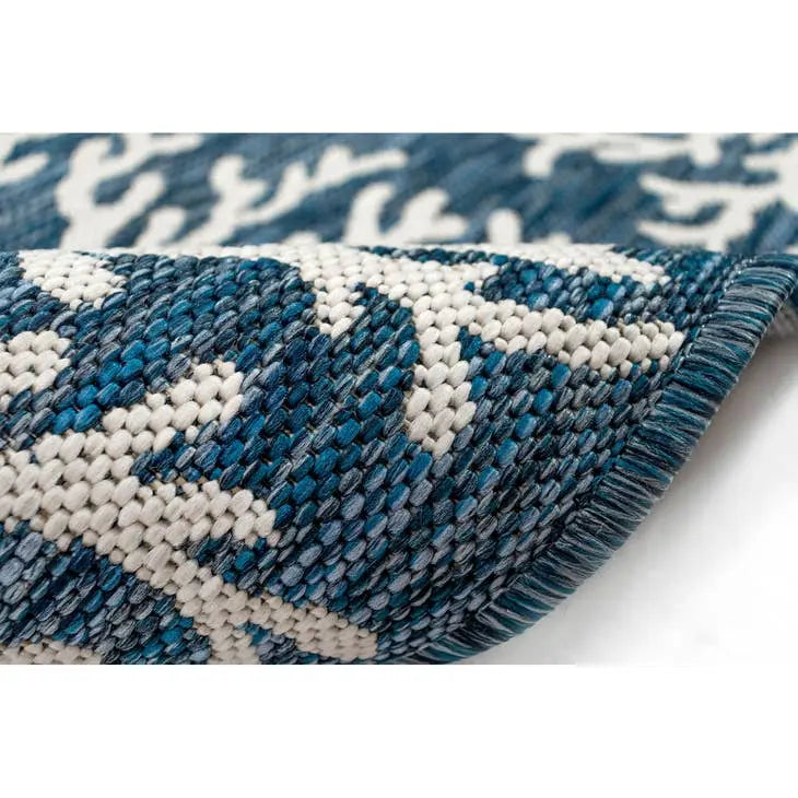 Close-up of a blue and white patterned coastal rug on a white background