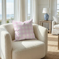 Lila Throw Pillow in pink gingham on a cream boucle chair with a coastal view.