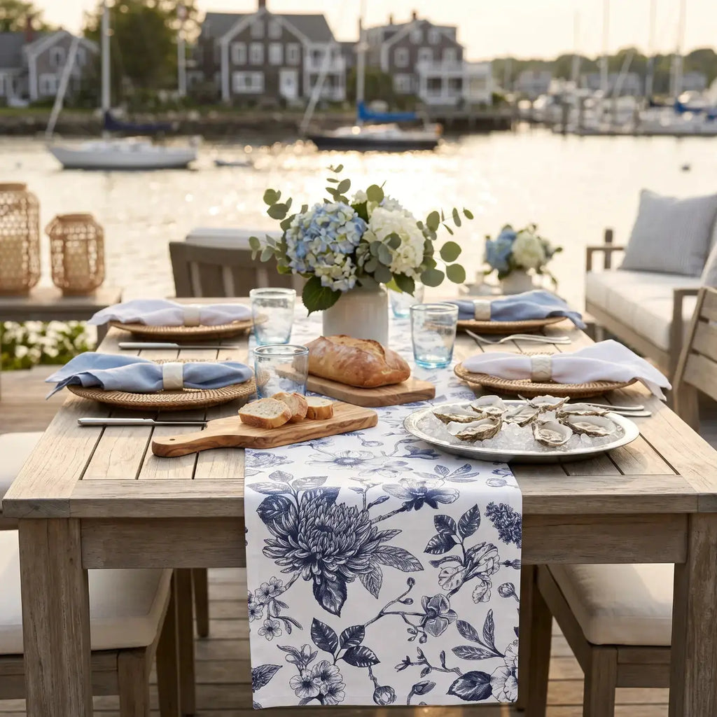 Chinoiserie blue and white floral table runner on a coastal dining table with white dishes.