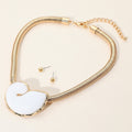 Chunky shell pendant snake chain necklace worn with a simple white top for a coastal look
