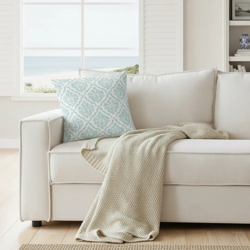 Valencia Damask Throw Pillow with aqua damask pattern on a cream sofa