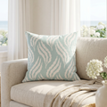 Coastal aqua leaf pattern pillow on a couch in a beach house style living room