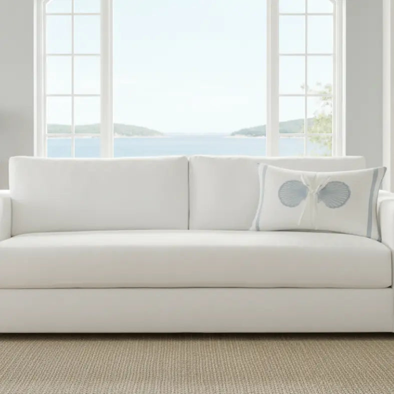 Coastal Seashell Decorative Lumbar Pillow (12 x 20, oblong) with two blue seashells tied by rope on a white sofa.