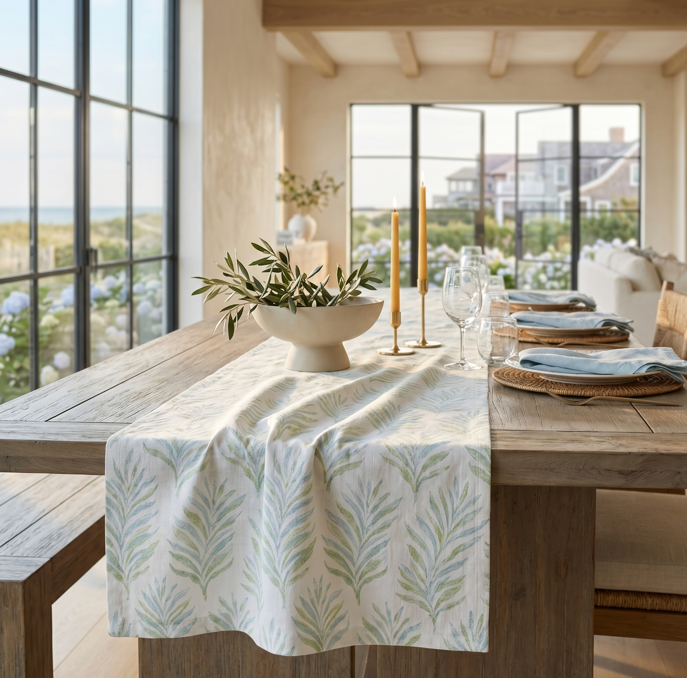Coastal blue and green leaf table runner styled on a light wood dining table with white dishes.