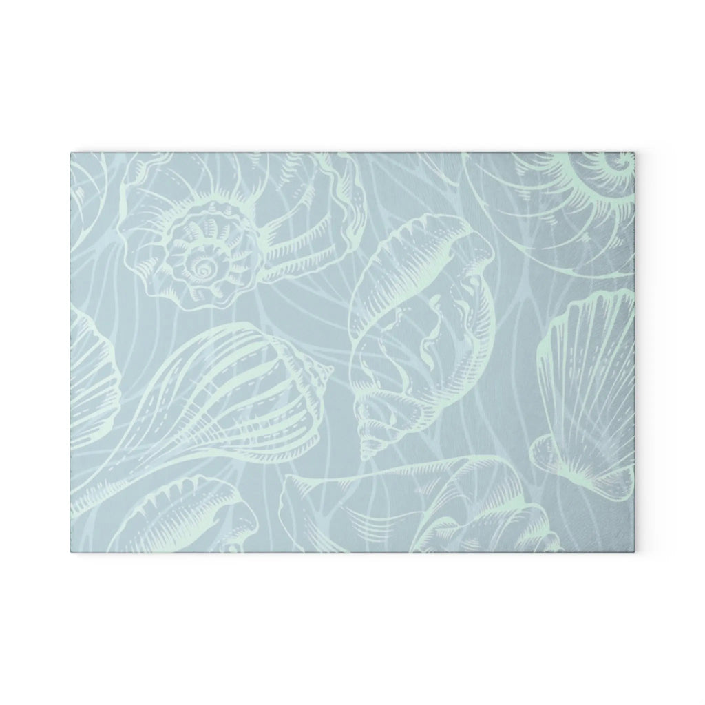 Tempered glass cutting board in seafoam tones with white seashell outlines.