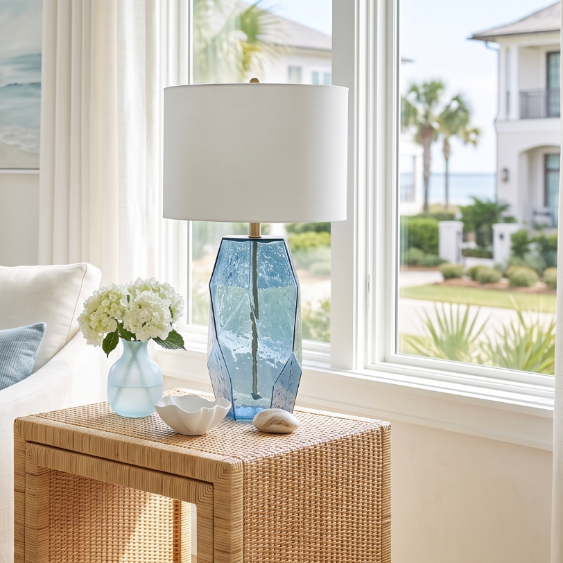 Coastal blue glass table lamp with brass hardware and a crisp white fabric drum shade.